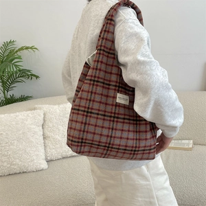 Close-up of vintage plaid wool tote bag worn over shoulder in cozy home setting