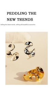 Close-up of abstract silver wavy earrings and golden ring with artistic metallic textures
