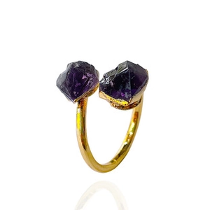 Detalle de un anillo dorado abierto con dos cristales de amatista púrpura en bruto