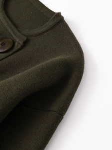 Détail du pull en tricot vert olive montrant la texture fine et le bouton en résine