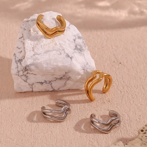 Detail of 18K gold and silver double-layer wave ear cuffs on marble textured stone