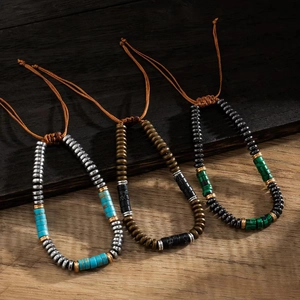 Three handmade beaded bracelets with turquoise, agate and malachite on wood surface