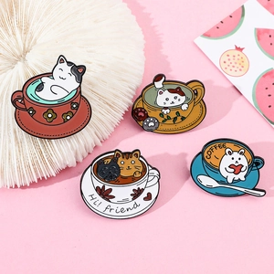 Detail shot of cute cat and rabbit enamel pins in colorful coffee cups on pink background