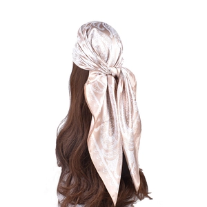 Detail of champagne paisley satin headscarf tied in a triangular style on mannequin