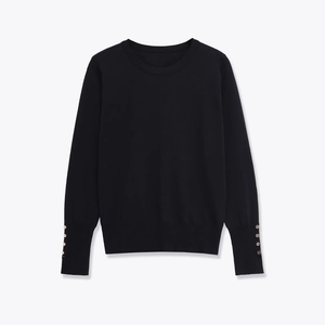 Close-up of black long sleeve knitwear showing golden decorative buttons on cuffs
