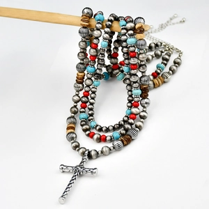 Close-up of layered turquoise beaded necklace with a large silver cross pendant detail