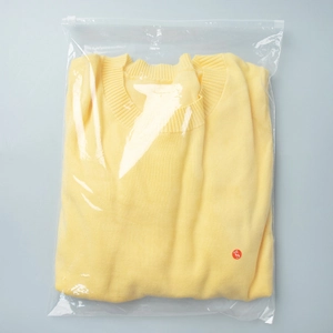 Detail of light yellow knit short sleeve top in transparent packaging with size S label