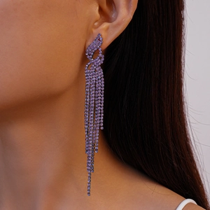 Close-up of model wearing long purple rhinestone tassel earrings with a silver needle post