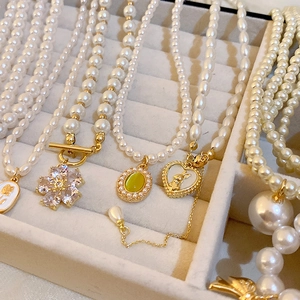 Détail de colliers de perles vintage avec breloques fleurs et cœurs dans un écrin
