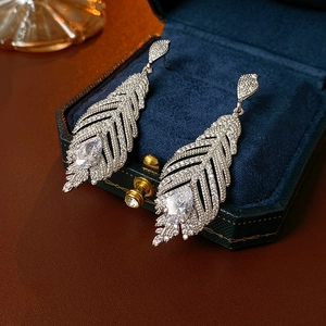Gros plan de boucles d'oreilles plumes en argent avec zircons dans un écrin en velours