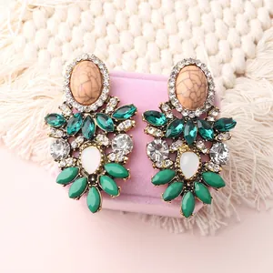 Macro view of vintage bohemian earrings with green crystals and marble stones on jewelry box