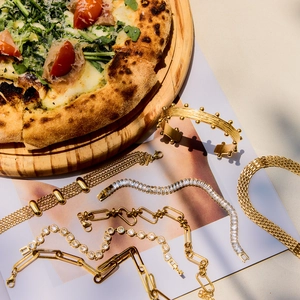 Creative flatlay of gold zircon bracelets and chains on magazines for a lifestyle look