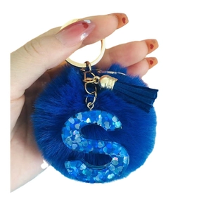 Blue pompom keychain with blue glitter letter S and tassel on a gold key ring