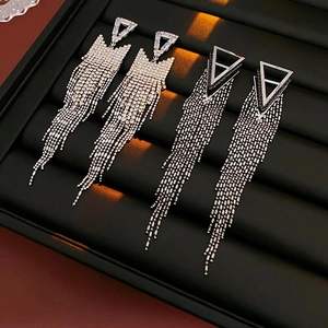 Close-up of silver and gunmetal triangle tassel earrings with sparkling rhinestones