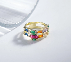 Detail van een brede gouden ring met kleurrijke regenboogzirkonia en witte accenten