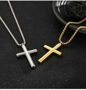 Close-up of minimalist gold and silver stainless steel cross pendants on dark background