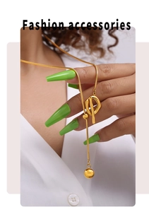 Close-up of golden stainless steel OT toggle necklace with a sleek polished ball pendant