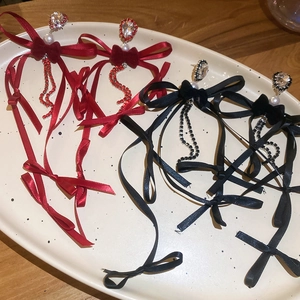 Détail de boucles d'oreilles nœud rouges et noires avec de longs glands en strass