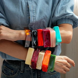 Stack of chunky acrylic resin bangles with colorful marble patterns worn by a model