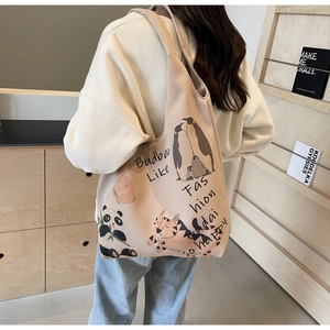 Detailed view of beige canvas tote bag with cartoon animal illustrations and shoulder strap