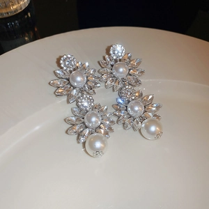 Detailed close-up of floral drop earrings with white pearls and sparkling crystals