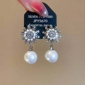 Detailed macro of S925 silver snowflake earrings with small zircons and a large pearl