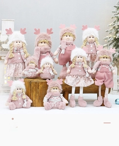 Detailed view of pink plush Christmas dolls with Nordic knitwear on snowy backdrop