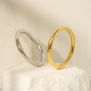 Detailed view of high-polished gold and silver minimalist bangles on a stone base