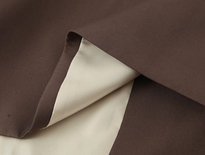 Detailed view of coffee brown and beige contrast fabric with fine plain weave texture