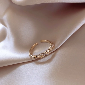 Adjustable golden twisted braid ring with sparkling zircon stones on soft satin fabric