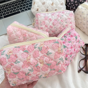 Close-up of quilted floral cosmetic bags with soft cotton texture and zipper detail