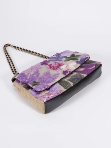 Detailed close-up of pink floral embroidery and sequins on a woven chain shoulder bag