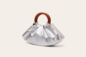 Detail of silver evening bag with crocodile texture, pleated design and brown wooden handle