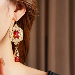 Detail of vintage palace style gold earrings with red stones on model's side profile