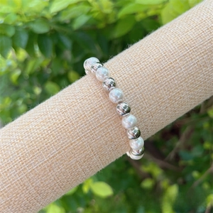 Close-up of elegant 18K gold plated copper and pearl beaded bracelet on burlap display