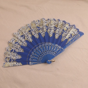 Detailed close-up of blue plastic folding fan with gold lace patterns on beige fabric