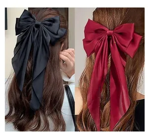 Detail of oversized satin bow hair clip with long ribbons in black and burgundy colors