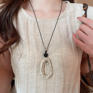 Détail du pendentif ovale en acrylique marbré avec perle noire sur collier long