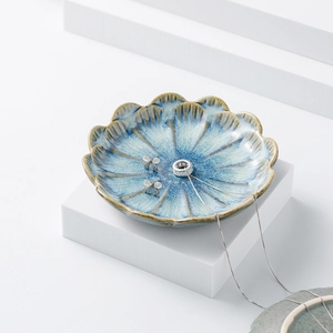 Detail view of blue lotus ceramic jewelry tray with silver necklace and bow earrings