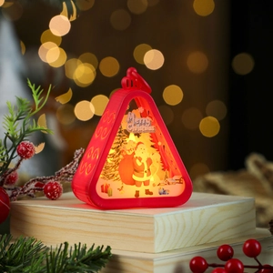 Detail of red vintage Christmas lantern with Santa scene on light wood surface