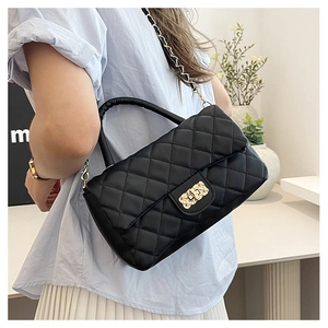 Detail of black quilted leather crossbody bag with gold chain strap and turn-lock closure