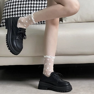 Gros plan de chaussettes blanches en dentelle à cœur avec chaussures en cuir à plateforme