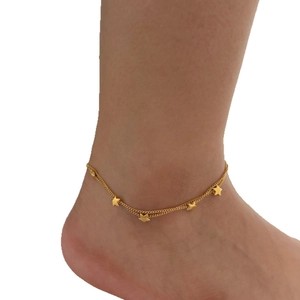 Minimalist gold multi-layer anklet with small star charms worn on woman's ankle