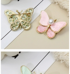 Detailed view of alloy butterfly brooches with marble resin wings and faux pearls