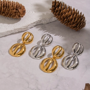 Modern hollow circular earrings in gold and silver finish, displayed on a marble surface