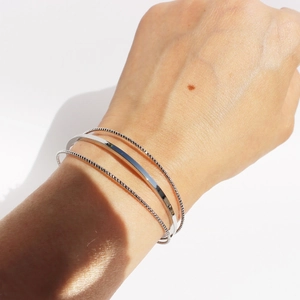 Minimalist silver geometric triple-layer line bangle set with polished finish on wrist