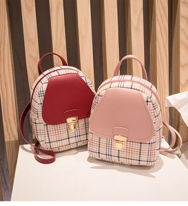 Detailed shot of two mini plaid backpacks in burgundy and pink with golden metal buckles