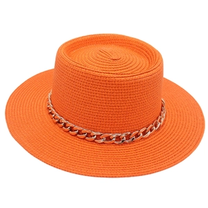 Macro view of bright orange woven straw hat featuring a stylish thick gold chain decoration