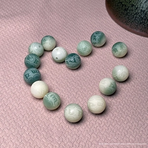Macro detail of white and green gradient Bodhi beads with carved Sanskrit runes