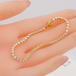 Close-up of golden tennis bracelet with round clear zircon stones and a secure box clasp